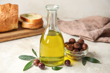 Bottle of fresh oil and bowl with olives on light background