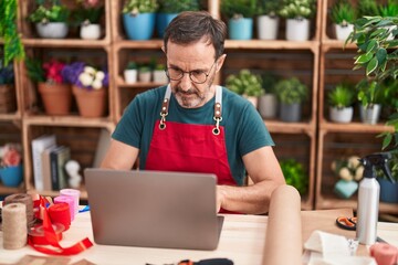 Middle age man florist using laptop at florist