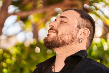 Young hispanic man smiling confident breathing at park