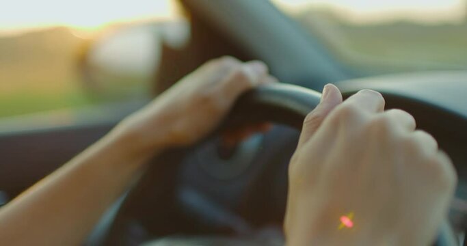 Close up female hands on steering wheel in car. Woman driving car goes on journey. Slow motion