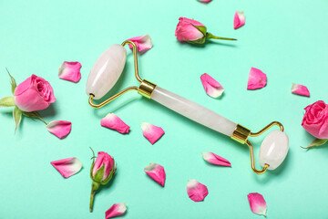 Facial massage tool with roses and petals on green background