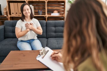 Hispanic girl with down syndrome doing therapy smiling with hands on chest with closed eyes and...