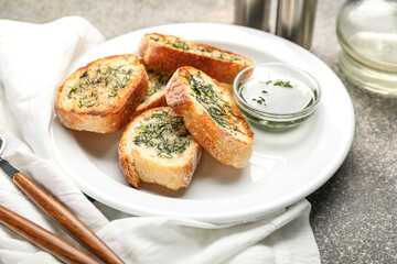 Plate with slices of toasted garlic bread and oil on grunge background, closeup