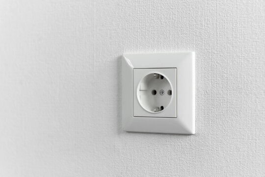 White electrical plastic socket on an isolated renovated wall of a new house. European electrical socket in the apartment close-up.
Repair and power supply of residential apartments. House wiring.