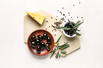 Composition with bowls of tasty black olives, cheese and spices on light background