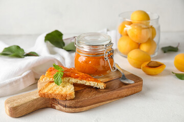 Wooden board of tasty sandwiches with apricot jam on light background