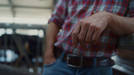 Worker livestock facility leaning fence posing camera in rural barn closeup.