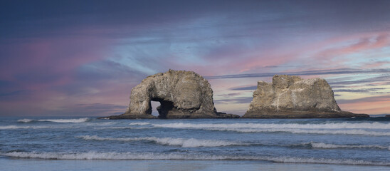 Costal Twin Rocks During Pink Sunset with small breaking waves 