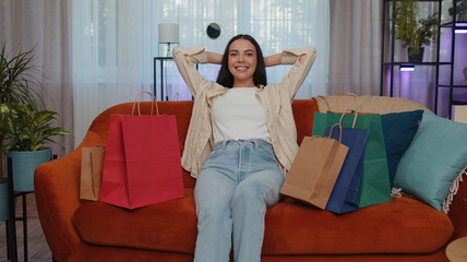 Obraz premium Portrait of caucasian adult girl happy shopaholic consumer came back home after shopping sale with bags. Young woman satisfied received parcels from online order at modern home apartment living room
