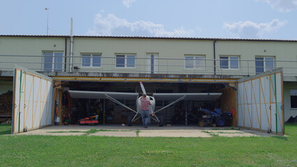 Aviator fixing airplane propeller inside repair hangar on countryside aerodrome.