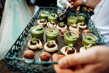 Snacks on a tray for a banquet. Green soup in small glasses