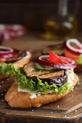 Delicious eggplant sandwiches served on wooden board, closeup