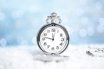 Fototapeta na wymiar Pocket watch on snow against blurred lights. New Year countdown