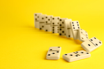 Falling white domino tiles on yellow background