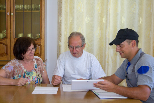 Image of an elderly couple checking documents and bills of a construction worker for home renovation work.
