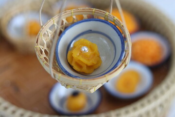 Hand holding Sweet Golden Cake recipe topping with sprinkles (Kanom Thong Ake in Thai language). Sweet traditional Thai dessert made of wheat flour, egg yolks, coconut milk and sugar. 