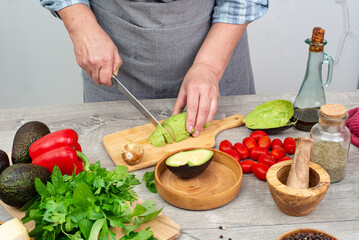 cook preparing avocado for serving. various vegetables and spices on the kitchen table