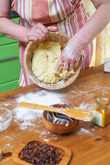 Female hands knead the dough in wooden bowl in the home kitchen. Close-up.