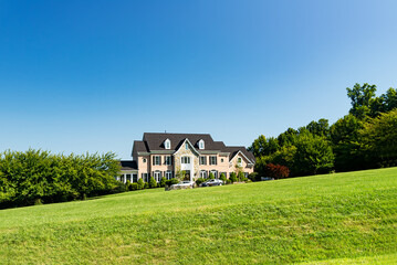 Fototapeta na wymiar Large country house and summer landscape with a perfect lawn. Blue sky and white clouds.