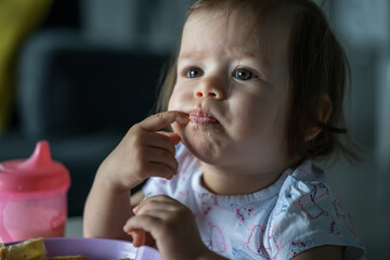 One girl small caucasian child sitting at the table at home alone eat having breakfast or lunch meal pastry alone in day real people growing up development concept copy space