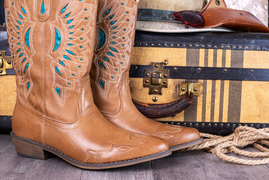 Women's cowboy boots and an old suitcase close-up.