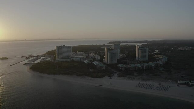 Orbit aerial of troia City hall and beach during huge sunrise over ferry working