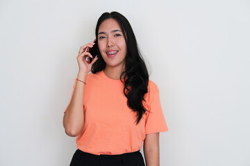 Young Asian women smiling to the camera while answering a mobile phone call