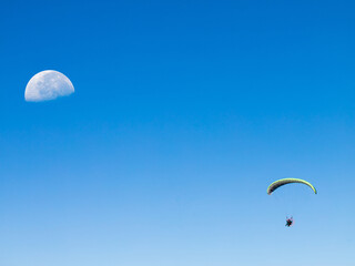 Blue sky with half moon and paraglider.