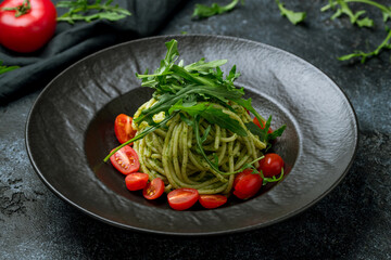 spaghetti pasta with pesto sauce and fresh tomatoes and aragula