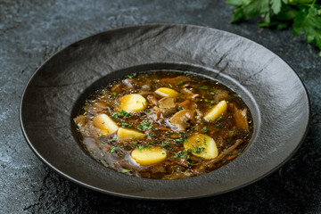 mushroom soup in black a plate on dark stone table