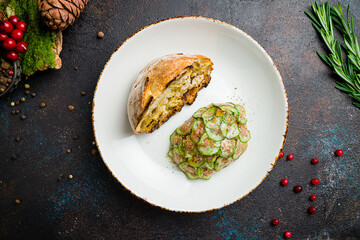 Tartare from beef with sliced cucumbers on plate on dark table top view