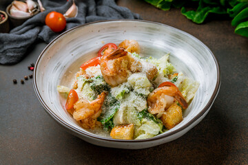 salad caesar with shrimps on plate on brown table
