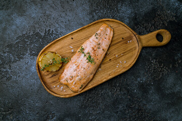 Salmon steak on the grill on board on dark stone table top view