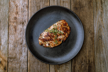 Grilled chicken Breasts on black plate on old wooden table