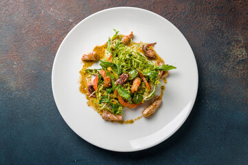 Salad with seafood on white plate on dark stone table top view