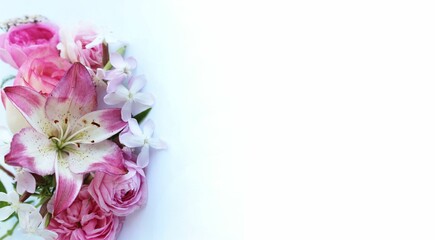 Delicate pink lilies and roses on a white background. Festive flower arrangement. Background for a greeting card.