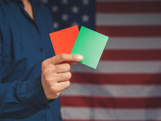 Close-up of hand businessman holding red and green color paper while standing over the American...