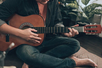 young man relax and playing guitar while sitting on sofa bed in living room at home.