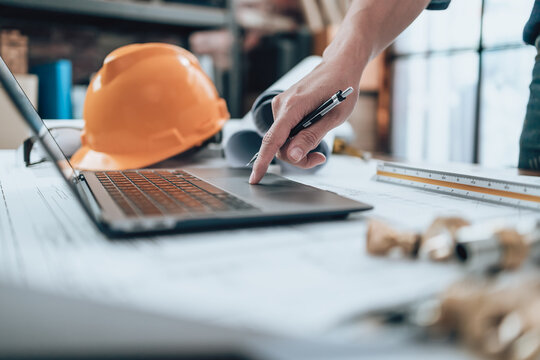 Engineering Working With Drawings Inspection On Laptop  In The Office And Calculator, Triangle Ruler, Safety Glasses, Compass On Blueprint. Engineer, Architect, Industry And Factory Concept.