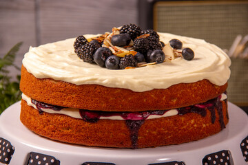 Vanilla cake decorated with whipped cream, red berries and almonds