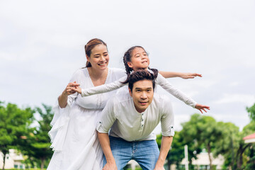 Portrait of enjoy happy love asian family father and mother holding hug cute little asian girl child smiling play and having fun moments good time in summer park at home