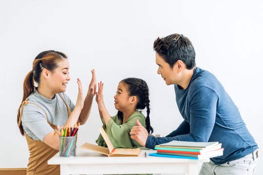 Portrait enjoy happy love asian family father and mother with little asian girl learn and study on table.Mom and dad with young girl writing with book make homework in homeschool at home.Education