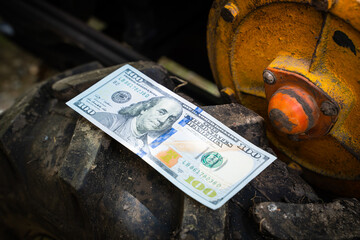One hundred dollars close-up lie on the wheel of a walk-behind tractor. The money lies on a tire...