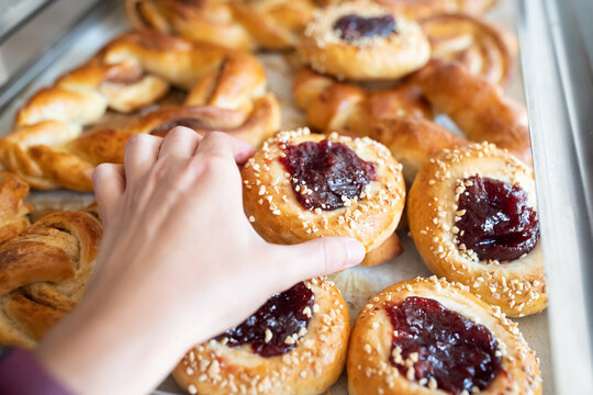 Sweet pastry made of wheat dough with fruit filling in the hands of the buyer. Front view.