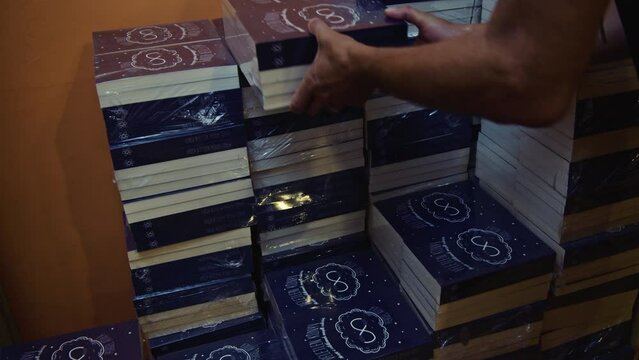 A man stacks books in the warehouse.
The title of the books translated into English: THE BOOK THAT HAPPENED