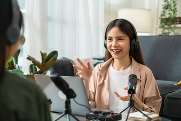 Young Asian woman use microphones wear headphones with laptop record podcast interview for radio. Content creator concept.