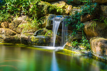 Japanese garden waterfalls. Lush green tropical Koi pond with waterfall from each side. A lush...