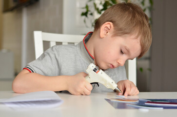 child glues a craft with a glue gun