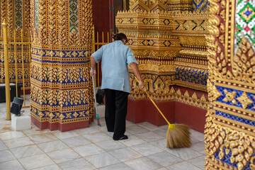janitor worker cleaning temple floor by sweeping