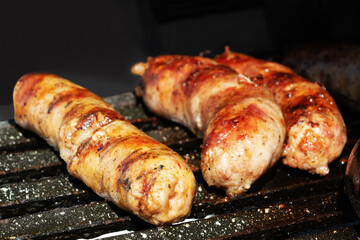 Three sausages cooking on the barbecue grill
